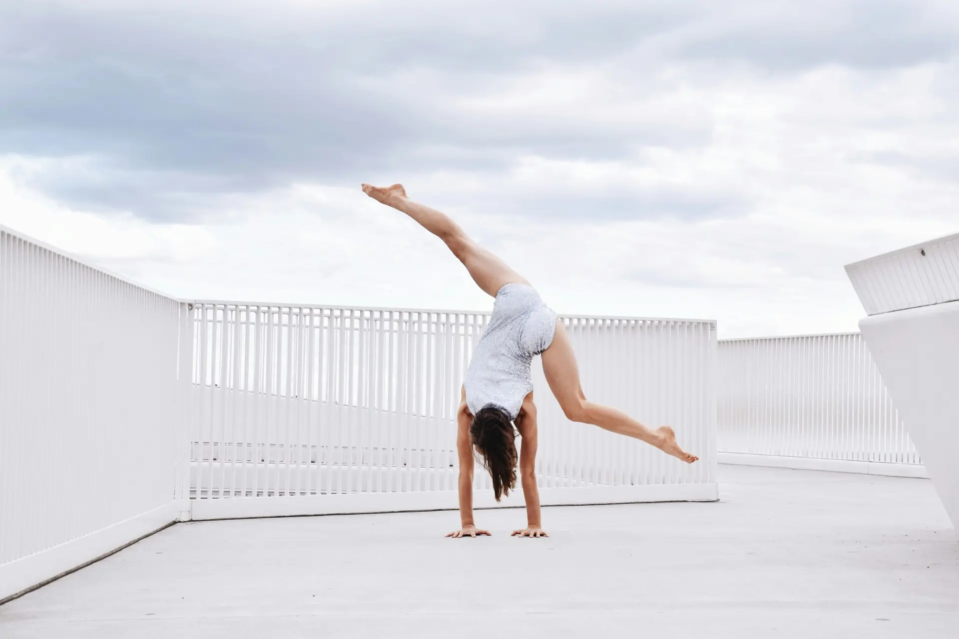 Female gymnast performing an elegant routine on the balance beam, showcasing strength and flexibility.