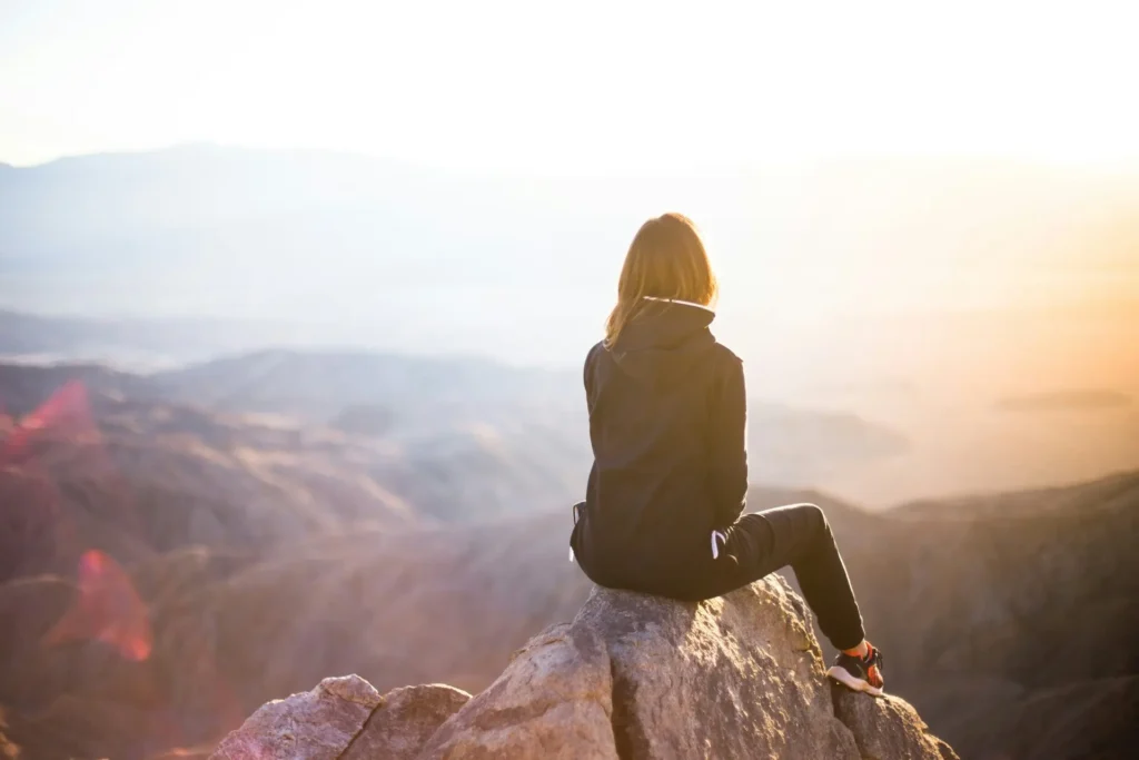 Adventurous woman scaling a challenging mountain peak, demonstrating endurance and determination in an outdoor environment.