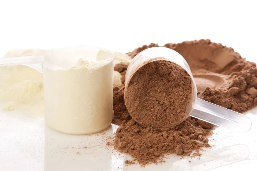 Scoops of chocolate and vanilla whey protein powder for fitness, muscle growth, and post-workout recovery supplements.