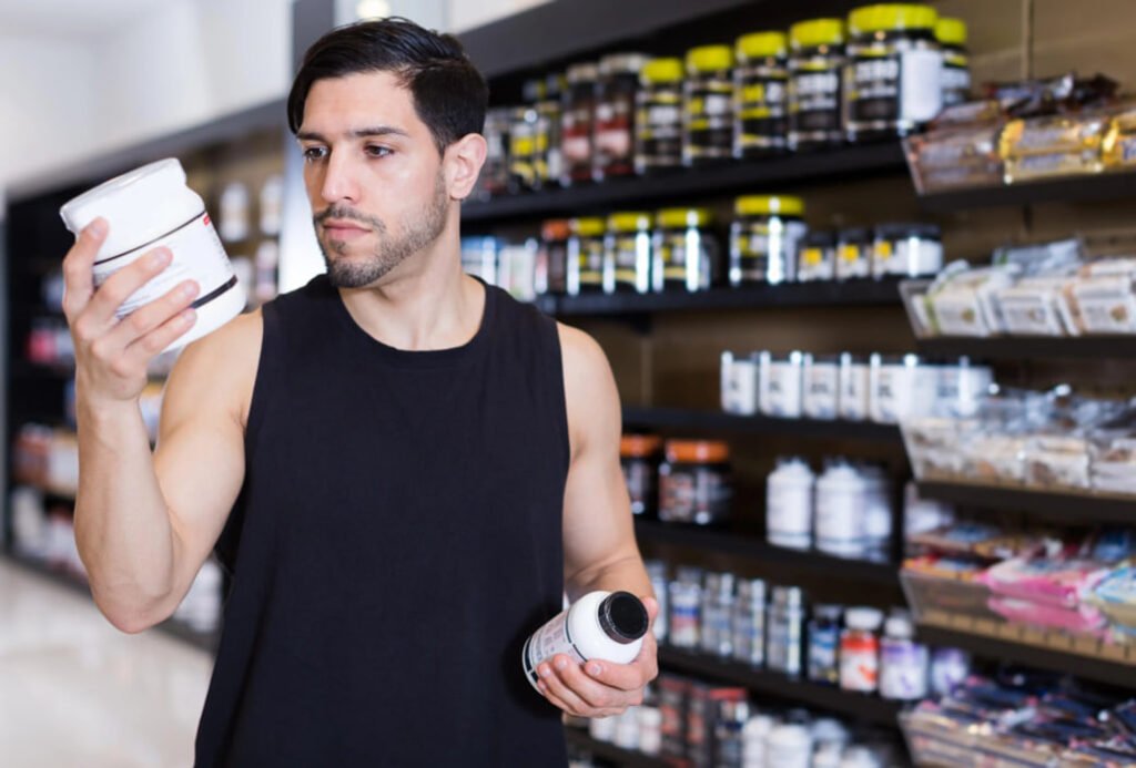 Adult man examining an unbranded supplement bottle beside a glass of water