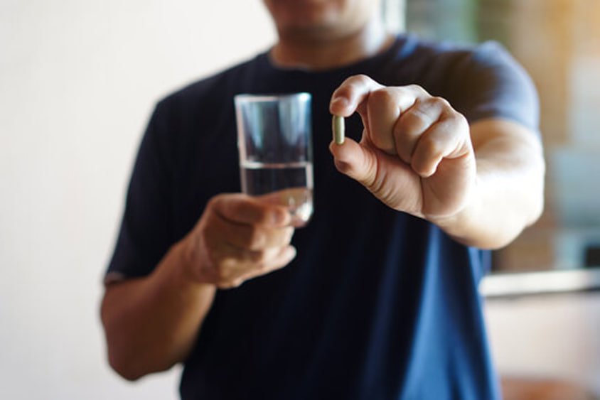 Man checking a supplement bottle label at a table