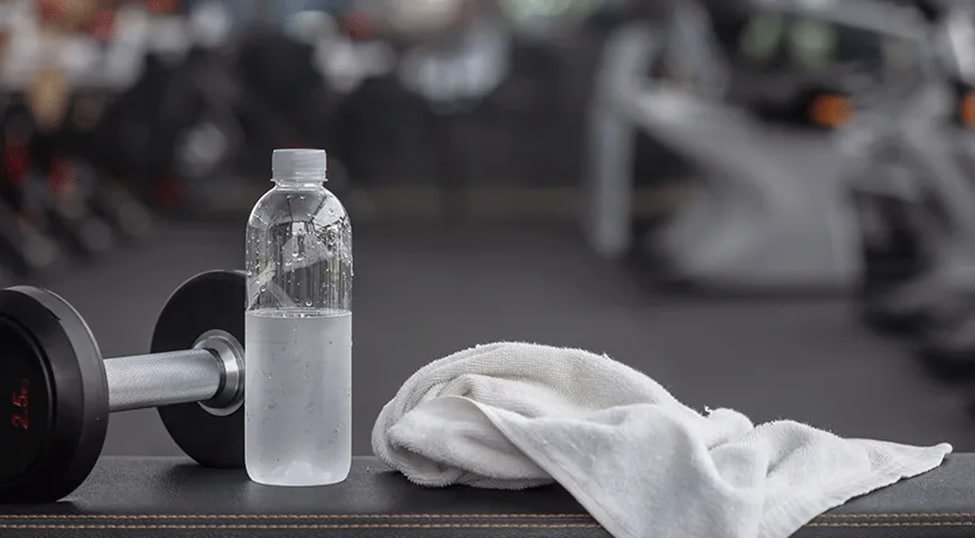 closed unbranded supplement bottles beside water and a gym bag
